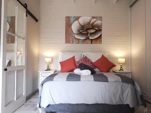 PlumsteadRAFTERS COTTAGE的卧室配有一张挂有花卉画的床铺。