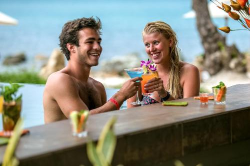 曾蒙海滩海之舞度假酒店的坐在桌子旁喝一杯的男人和女人