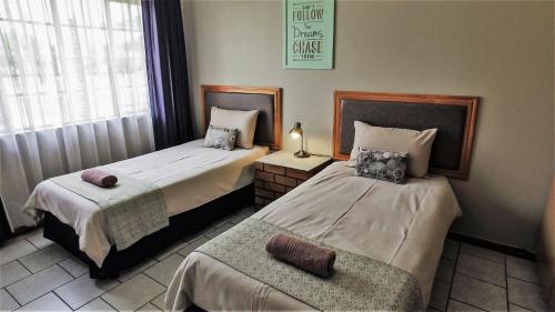 贝拉贝拉Hoogland Spa Resort Bela Bela的一间卧室配有两张床和椅子