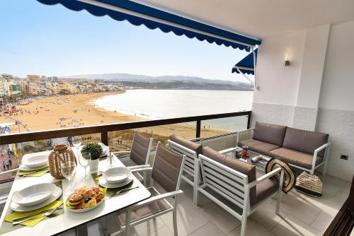 大加那利岛拉斯帕尔马斯Apartamentos Don Carlos的阳台配有桌椅,享有海滩美景。