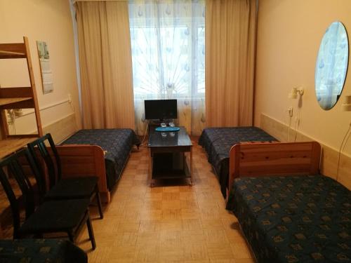 塔林马赫特拉酒店的客房设有三张床、一张桌子和电视。