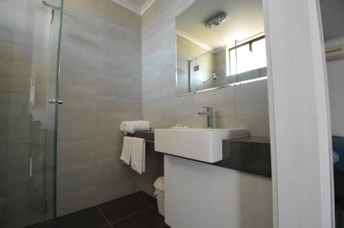 天鹅山帕鲁纳汽车旅馆的一间带水槽和玻璃淋浴的浴室