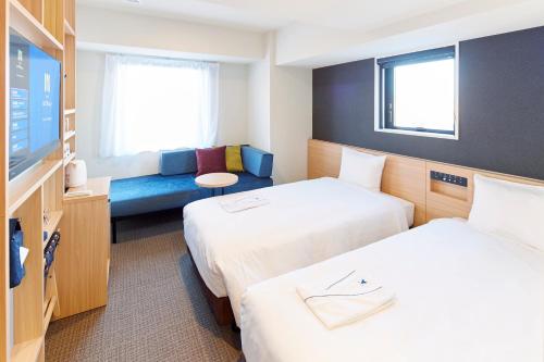 东京hotel MONday Tokyo Nishikasai的一间酒店客房,设有两张床和电视
