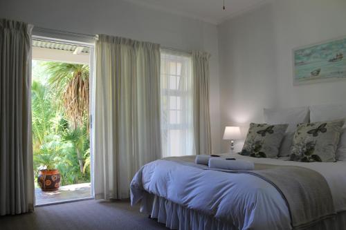 奥茨胡恩van Biljon Cottage No Loadshedding的一间卧室设有一张大床和一个滑动玻璃门