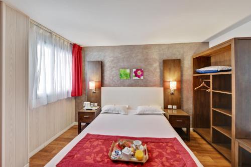 维勒瑞夫HOTEL PARIS PACIFIC VILLEJUIF- INSTITUT GUSTAVE ROUSSY et Direct PARIS的一间卧室配有一张红色地毯的床