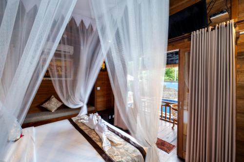 蓝梦岛蓝梦岛光辉日落别墅度假村 的一间带白色窗帘的卧室和一个阳台