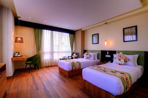 西里古里Udaan Clover Hotel Banquet & Spa的酒店客房配有两张床和一张书桌