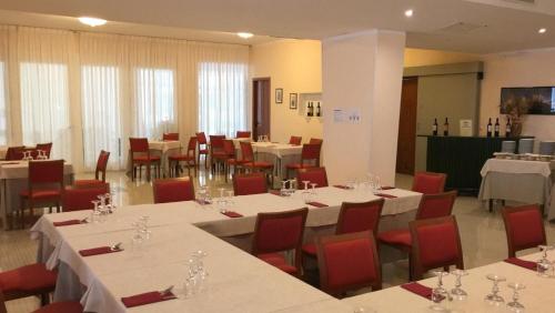 布林迪西密涅瓦酒店 的用餐室配有白色的桌子和红色的椅子