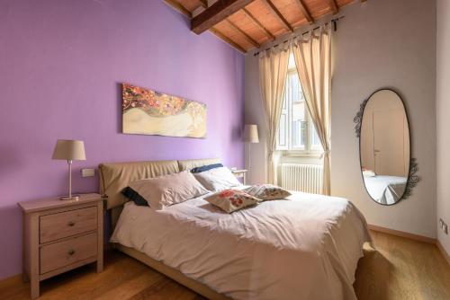 阿雷佐In Arezzo Apartment的一间卧室设有紫色的墙壁和一张带镜子的床