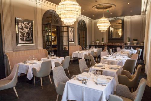 讷莱米讷The Originals Boutique, La Maison Rouge, Lens Ouest (Qualys-Hotel)的餐厅设有白色的桌椅和吊灯。