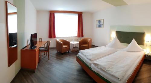 OlbersdorfHotel Haus am See的一间卧室配有一张床、一张书桌和一台电视