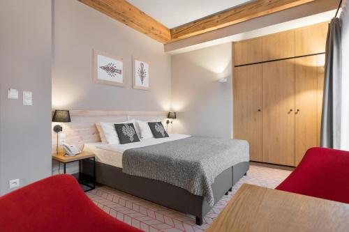 扎科帕内Hotel Foluszowy Potok的一间卧室配有一张床和两张红色椅子