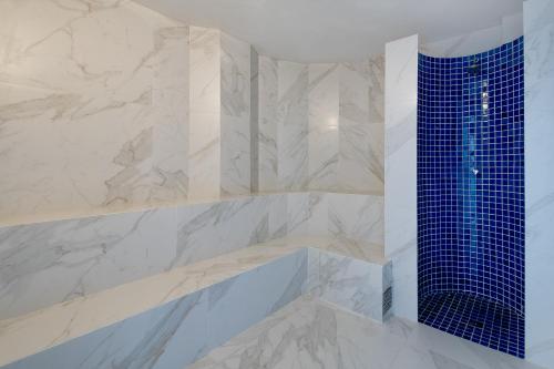 马瑙斯马瑙斯千年酒店的浴室拥有白色的大理石墙壁和蓝色的瓷砖淋浴。