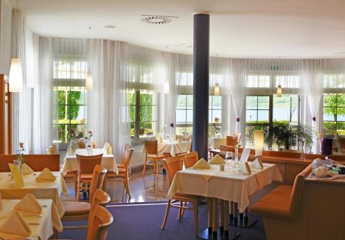 OlbersdorfHotel Haus am See的餐厅设有桌椅和窗户。