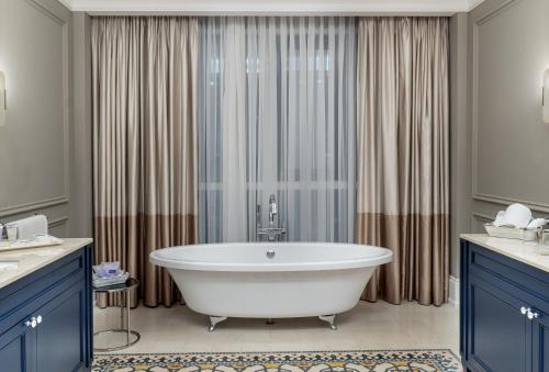 安曼安曼华厦酒店及会议中心的带浴缸的浴室和蓝色橱柜