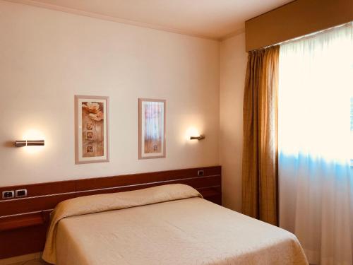 锡尼亚德尔菲娜酒店的一间卧室设有一张床和一个窗口