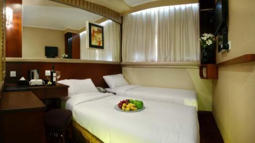 香港东方泛达酒店的一间设有两张床的房间,上面放着一碗水果