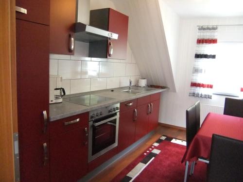 法尔维希Ferienwohnung Morgen的一个带红色橱柜和水槽的小厨房