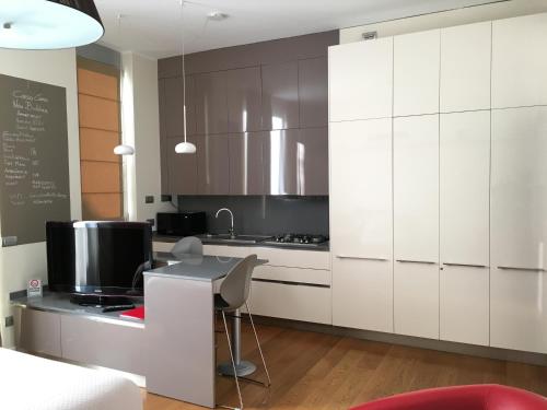 米兰Corso Como New Building Apartment的厨房配有白色橱柜和带电脑的书桌