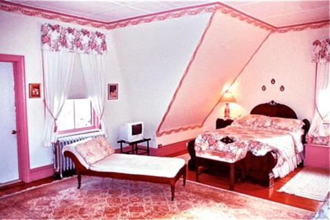 莱诺克斯惠斯勒旅馆的粉红色的卧室配有床和椅子