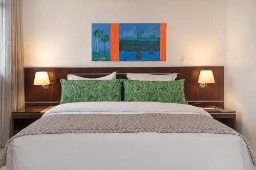 马瑙斯马瑙斯千年酒店的一间卧室配有一张带绿色枕头的大床