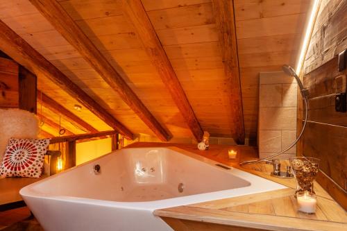 采尔马特Chalet Schuler的设有一个大型白色浴缸,位于带木制天花板的房间内