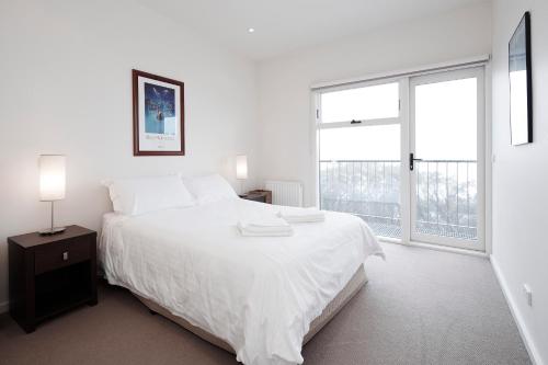 布勒山K2 14号公寓的白色的卧室设有一张大床和一个窗户