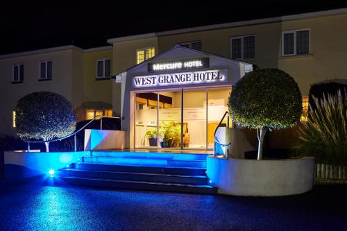 萨彻姆Mercure Newbury West Grange Hotel的夜间拥有蓝色灯光的西门车库酒店