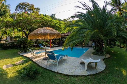 尼泰罗伊Pousada Pedras Brancas的庭院内的游泳池,配有椅子和遮阳伞