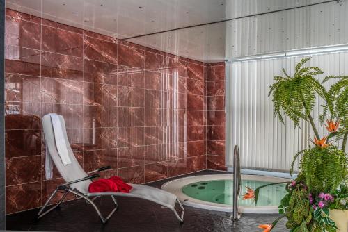 萨斯阿尔马格尔Wellness- und Schneesporthotel Christiania的一间带椅子和浴缸的浴室