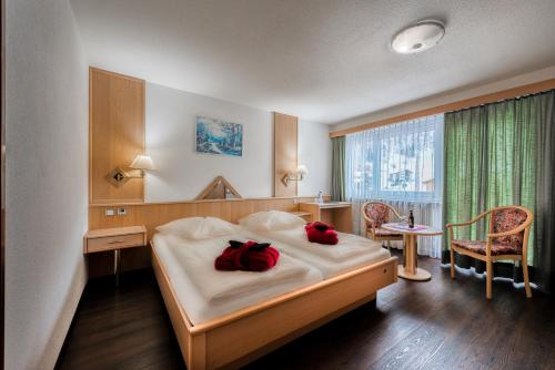 萨斯阿尔马格尔Wellness- und Schneesporthotel Christiania的一间卧室配有一张带两个红色枕头的床