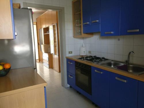 托雷阿马莱VILLA AZZURRA的厨房配有蓝色橱柜和不锈钢冰箱