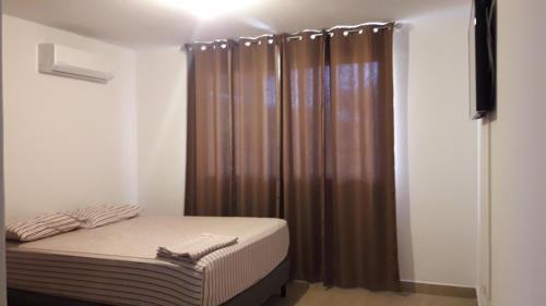 El Llano del MedioCoronado Beach Paradise的一间小卧室,配有床和棕色窗帘