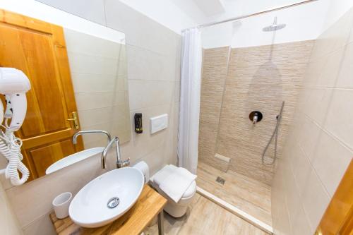 地拉那男爵酒店的浴室配有卫生间、盥洗盆和淋浴。