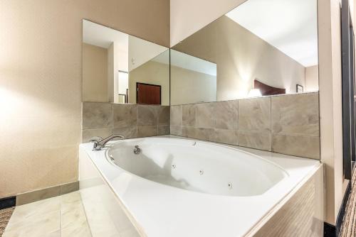 矿泉井城Red Lion Inn & Suites Mineral Wells的浴室配有大镜子和白色浴缸