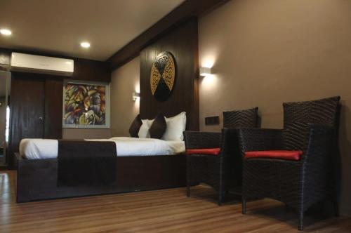 巴罗达Hotel Stellar的酒店客房,配有一张床和两把椅子