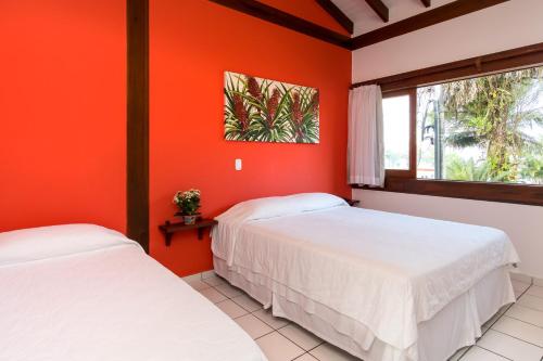 乌巴图巴Pousada Peixes do Mar的橙色墙壁客房的两张床