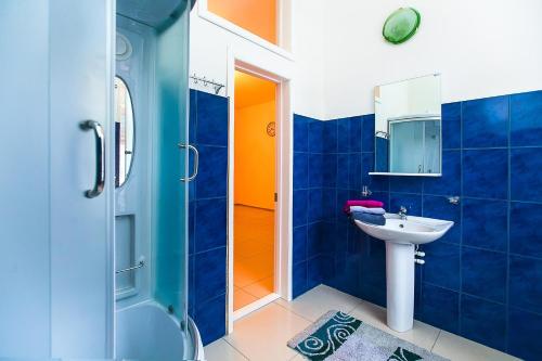 托木斯克猎人之家旅舍的蓝色的浴室设有水槽和淋浴
