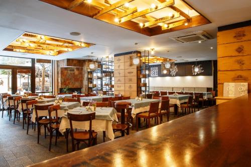 班斯科Hotel Casa Karina Bansko - Half Board & All Inclusive的一间带桌椅的餐厅和一间酒吧
