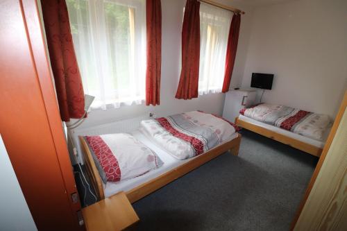 贝德日霍夫乌里斯基豪拉克酒店的配有窗户和红色窗帘的客房内的两张床