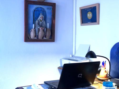 舍夫沙万达达迪奇雷夫摩洛哥传统庭院住宅的一张桌子,上面有一台笔记本电脑和一张宗教图片