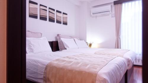 京都COCORO HOTEL的一间卧室设有两张带白色床单的床和窗户。