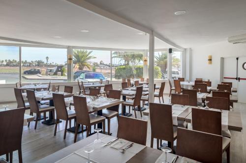 普拉亚布兰卡Sandos Atlantic Gardens的餐厅设有桌椅和窗户。