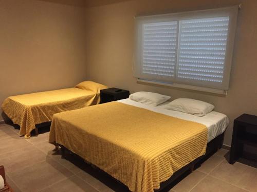 贝拉维斯塔Aires de Río的一间卧室设有两张床和一个带百叶窗的窗户。
