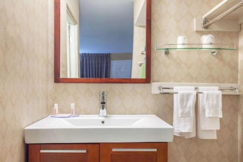 金斯顿Howard Johnson Inn by Wyndham Kingston的浴室配有盥洗盆、镜子和毛巾