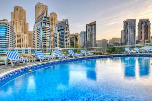 迪拜Pearl Marina Hotel Apartments的一个带椅子的游泳池,享有城市天际线