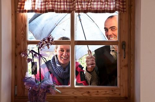 Balbido-rangoAgritur Maso Pra' Cavai B&B的两个男人,一边用雨伞从窗户望出去