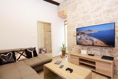 希贝尼克XY Suites - Design Apartments的客厅配有大屏幕平面电视,位于石墙上