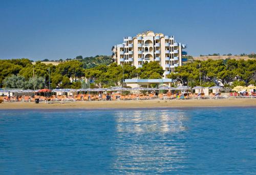 朱利亚诺瓦帕克德普林西比酒店的海滩上的酒店,配有椅子和遮阳伞