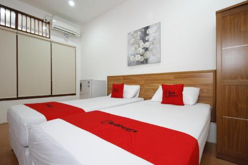 雅加达印度尼西亚广场红门旅馆的宿舍间内的两张床,配有红色枕头
